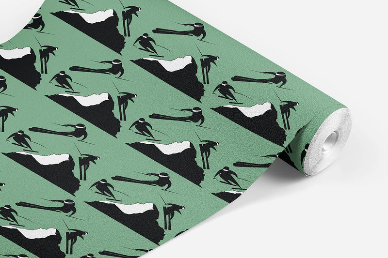 roll of Off Piste wallpaper which has black and white skiers on either side of a mountain on an alpine green background